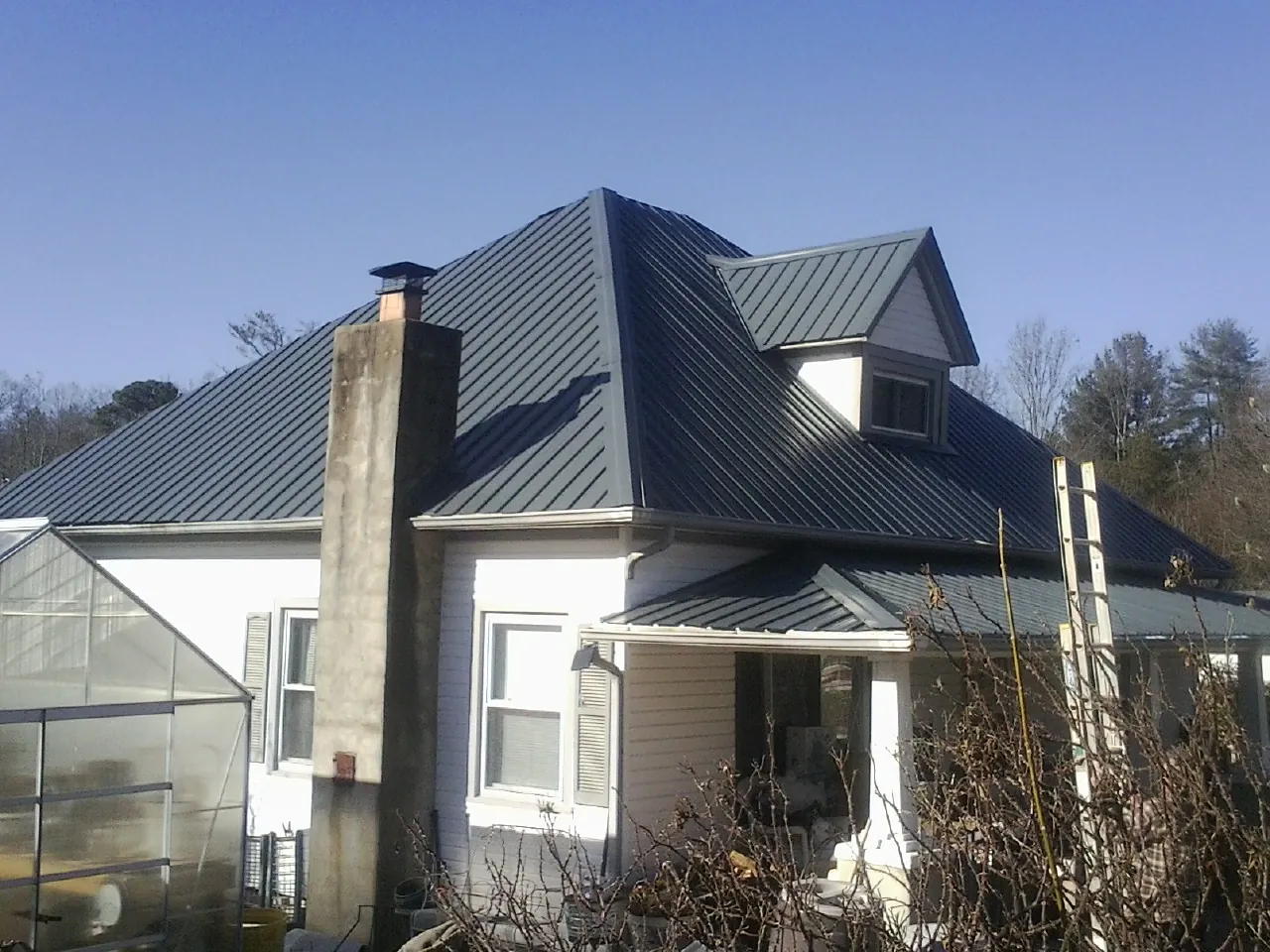 Dark blue standing seam metal roof on a white farmhouse with dormer — Slate & Tile Roof Repair by Roofing Brothers in Morrisdale