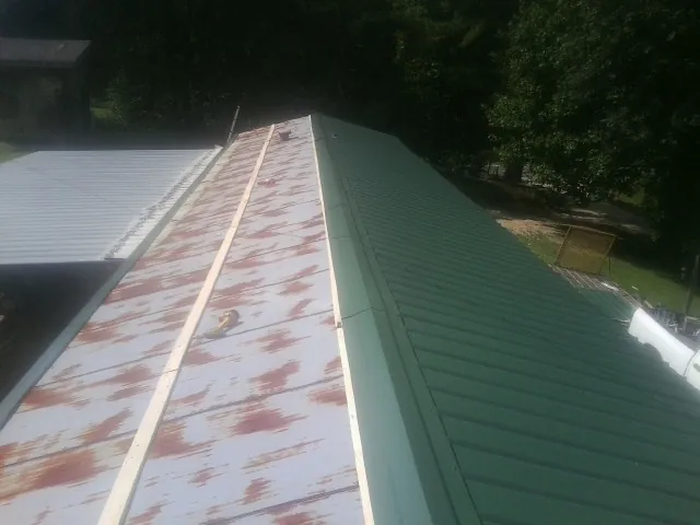 Old rusted panels beside newly installed green metal roofing — Wind Damage Roof Repair by Roofing Brothers in Morrisdale