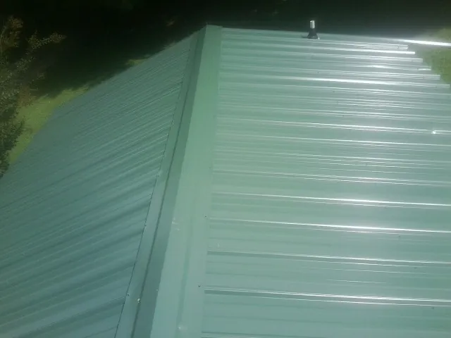 New green metal panels meeting at the ridge of a roof — Flat Roof Repair work by our crew in Morrisdale
