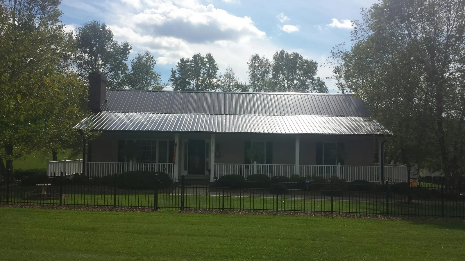 Gray metal roof on a brick ranch with a full width front porch — Gutter Guard Installation work by our crew in Morrisdale
