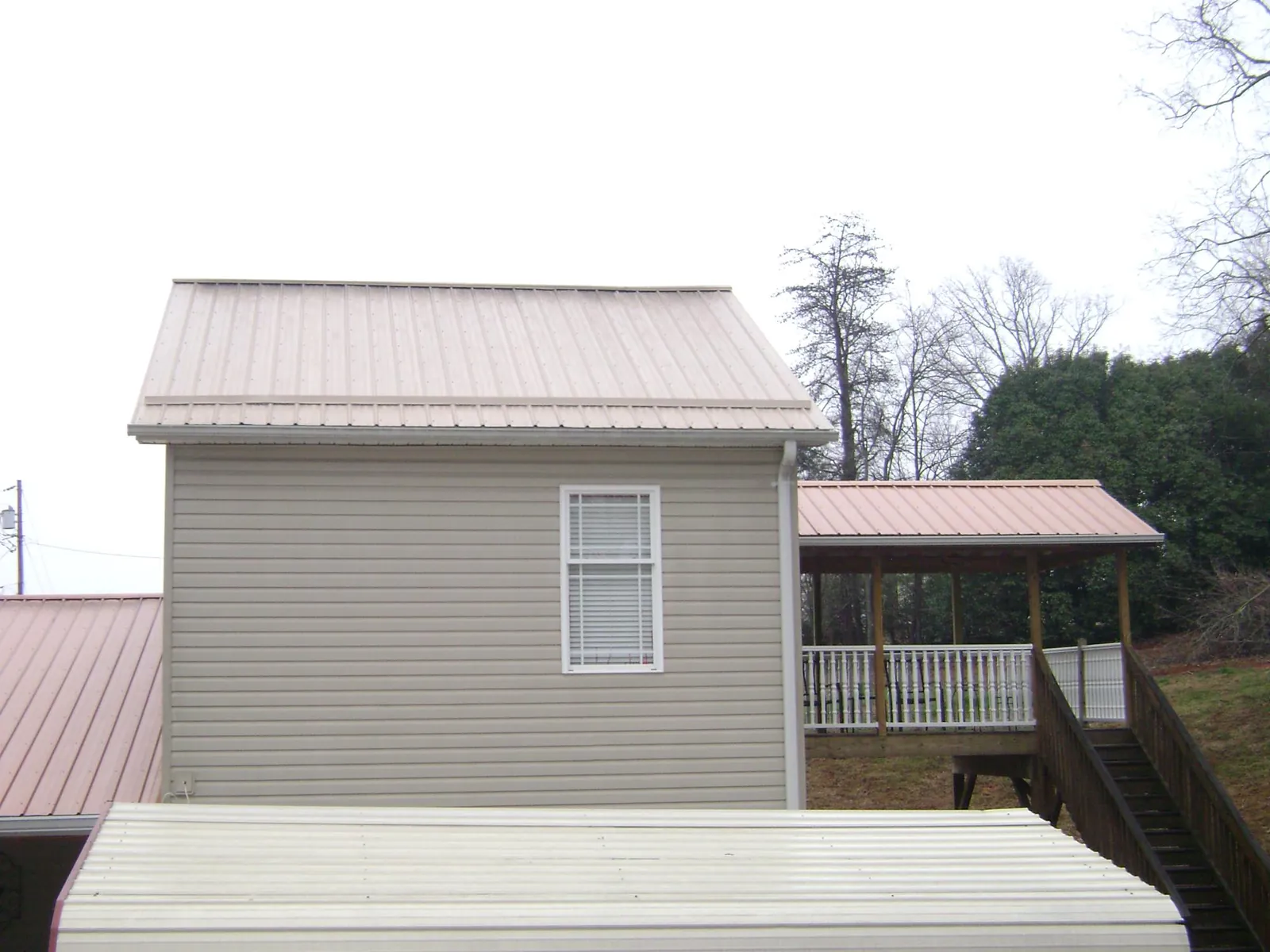 Tan metal roofs on a two story addition and attached porch, from a Roof Replacement job in Morrisdale