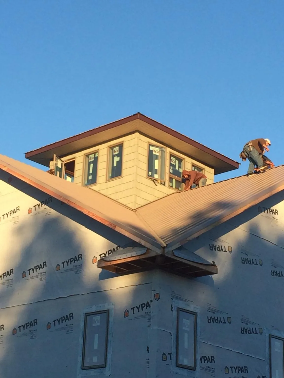 Roofers working around a rooftop cupola on a new metal roof at sunset — Roof Waterproofing in Morrisdale by Roofing Brothers